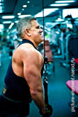 Поясное фото мужчины и мышц трицепса при силовом упражнении на блочном тренажере