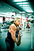 Фото мужчины во время силового упражнения на трицепс на блочном тренажере в спортзале