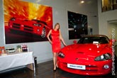 Фото плаката Dodge Viper и девушки модели в красном платье рядом с красным купе Dodge Viper SRT-10