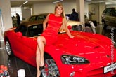 Фото красивой девушки блондинки, сидящей на капоте красного купе Dodge Viper
