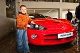 Фото мальчика рядом с красным Dodge Viper