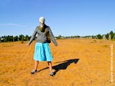 Фото девушки в противогазе в полный рост, стоящей на пустом поле