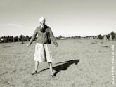 Черно-белое фото девушки в противогазе в полный рост, стоящей посреди поля