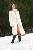 Модная фотография девушки в белом пальто (стоящей в снегу) для рекламы каталога одежды