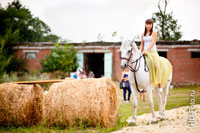 Фото девушки верхом на белой лошади рядом с тюками сена
