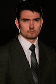Мужской портрет в темном костюме, белой рубашке и галстуке на черном фоне