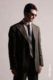 Фото мужчины в солнечных очках и деловом костюме на сером фоне в студии