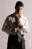 Поясной портрет мужчины в рубашке, завязывающего галстук