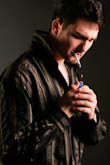 Фото мужчины в студии, прикуривающего сигарету зажигалкой