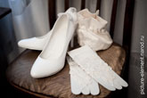 Фото свадебных туфель невесты, белых перчаток рядом и сумочки