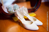 Фото белых свадебных туфель невесты на полу у зеркала