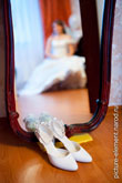 Фото свадебных туфель на полу у зеркала, в зеркале - отражение невесты вдали