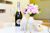 Фото туфель невесты на столе, вдали - шампанское с бокалами и букет