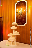 Фото свадебного торта на столе у стены и свечей на стене