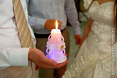 Фото горящей свадебной свечи семейного очага на фоне жениха и невесты в расфокусе