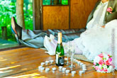 Свадебный натюрморт: свадебные свечи на полу в форме сердца, в центре которого - бутылка шампанского с бокалами, вдали - жених и невеста
