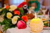 Горящая свеча на фоне цветов на свадебном столе