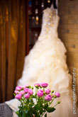 Фото букета из роз на фоне белого платья невесты
