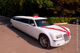Фото белого свадебного лимузина Крайслер (Chrysler) с кольцами на крыше и лентами на капоте