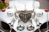 Фото передка старинного свадебного лимузина: птичка на капоте, радиаторная решетка в форме сердца, фары и клаксоны