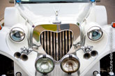 Фото старинного свадебного лимузина спереди: решетка радиатора в форме сердца, фары, клаксоны