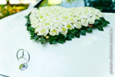 Фото знака-логотипа Mercedes на капоте и сердца из белых роз на свадебном авто