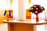 Фото стола в зале бракосочетаний: свадебный букет на столе, флаг России и другие предметы