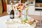 Фото бутылки Мартини с бокалами на столе, обручальных колец на подушке, букета невесты, коробки с чулками невесты и букв «Свадьба»