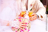 Фото руки невесты с обручальным кольцом на букете невесты, бокалов с шампанским в руках на дальнем плане