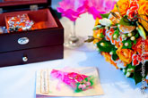 Фото золотых обручальных колец сверху на открытке, справа - букет невесты, вдали - деревянная шкатулка с украшениями
