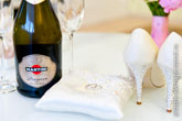 Фото бутылки Мартини, обручальных колец на белой подушке, каблуков туфель невесты