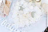 Свадебный фото натюрморт в светлых тонах: обручальные кольца в центре сердца из белых роз